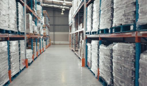 Logistics man and trolley in warehouse with packaging storage and shelf